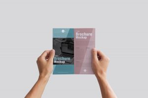 Free-Man-Holding-Brochure-in-Hands-Mockup-PSD